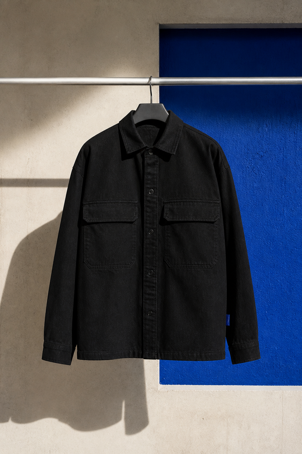 A clean black overshirt in an editorial product composition.